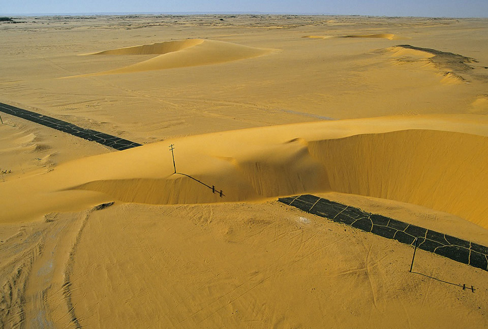 road interrupted by a sand dune