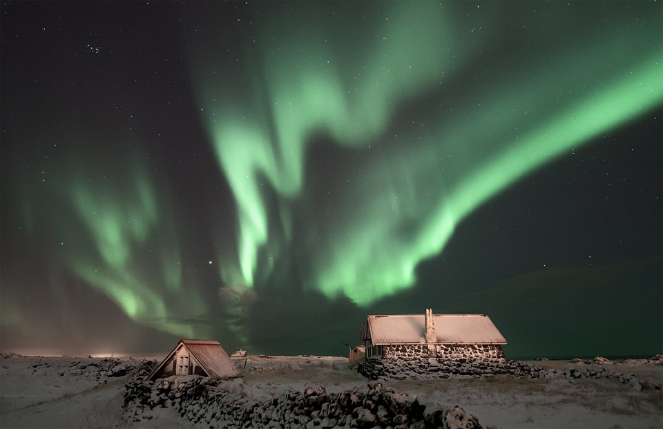 aurora borealis over cabins in iceland