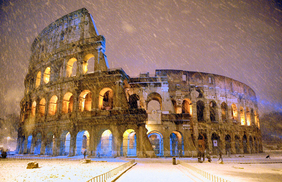 snowfall over colosseum in rome, italy