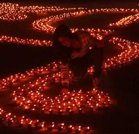 girl lights earthen lamps, india