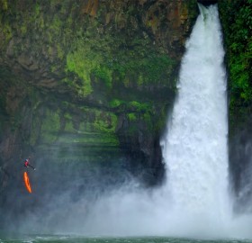 man jumps from a cliff next to a waterfall, veracruz, mexico