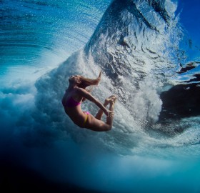 girl swimming underneath wave